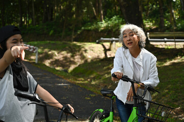 An elderly woman takes a break from cycling while her granddaughter excitedly points out the scenic...