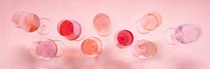 Rose wine panorama, overhead flat lay shot, a variety of hues and tints, on a pink background, many wine glasses, panoramic banner