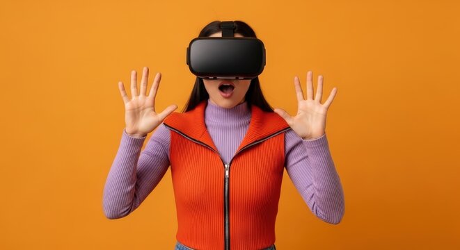 Woman wearing vr headset with hands raised on orange colored background - Powered by Adobe
