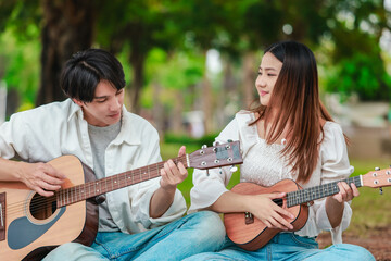 Asian Couple Playing Guitar Outdoors