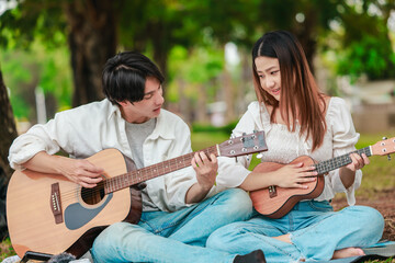 Asian Couple Playing Guitar Outdoors