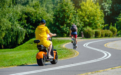 A guy rides an electric scooter in the summer Park
