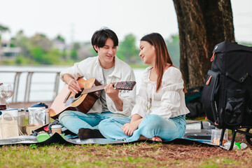 Asian Couple Playing Guitar Outdoors