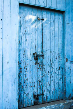 Locked and bolted old blue wooden door with paint peeling off