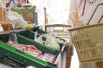 スーパーの野菜コーナーで買い物をする女性