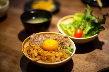 A close up side dish tomato green salad Japanese kyudou grilled pork with Marinated egg yolk and rice bowl serve with salted pickled egg yolk and miso food set 