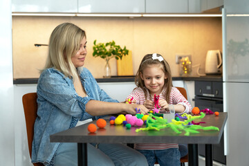 Happy family create handmade craft. Mother and little daughter make diy from colored chenille wire toys. Leisure with children. Education