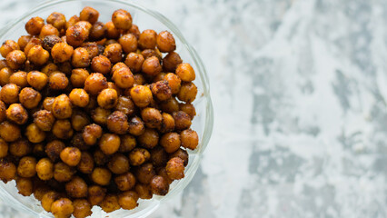 Delicious baked chickpeas in a transparent bowl on a light background with space for text flatlay....