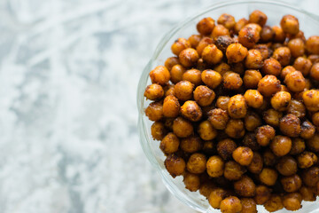 Delicious baked chickpeas in a transparent bowl on a light background with space for text flatlay....