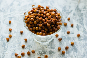 Delicious baked chickpeas in a transparent bowl on the table, on a light background with space for...