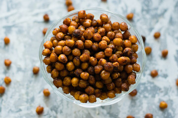 Delicious baked chickpeas in a transparent bowl on the table, on a light background with space for...