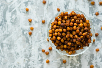 Delicious baked chickpeas in a transparent bowl on the table, on a light background with space for...