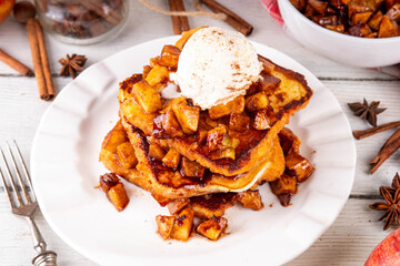 Sweet breakfast Apple Pie French Toast. Tasty delicious Stuffed French Toast with apple pie filling, cinnamon and ice cream scoop on top, with spices and fresh apples on table background