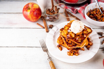 Sweet breakfast Apple Pie French Toast. Tasty delicious Stuffed French Toast with apple pie filling, cinnamon and ice cream scoop on top, with spices and fresh apples on table background