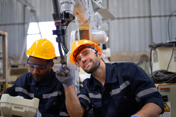 Blue collar workers at machine shop with welding robot arm.