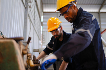 Blue collar workers at machine shop with welding robot arm.