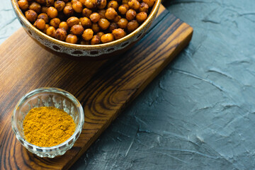Delicious snack, fragrant baked with curry spices and smoked paprika chickpeas in a brown bowl and...
