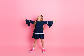 Happy young girl in a stylish blue dress posing playfully against a vibrant pink background