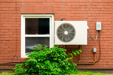 mini split air conditioner / heat pump exterior unit monuted on the brick wall of an older...