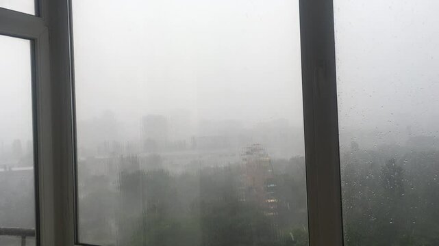 Heavy rain behind the window. Heavy raindrops hitting the glass, low visibility, monsoon season.