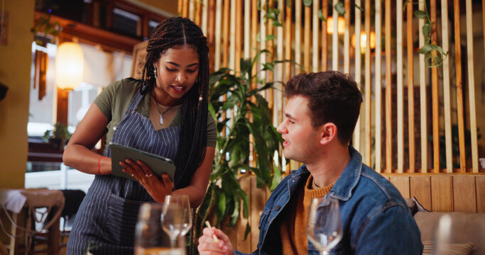 Man, listen and waitress with tablet at restaurant for menu, order price and reading information. Customer, server and digital for food choice, online selection and hospitality service for lunch date
