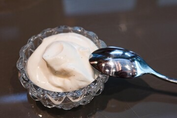 close up of cream in a flora transparent grand glass with a tea spoon, for adding to bread or coffee