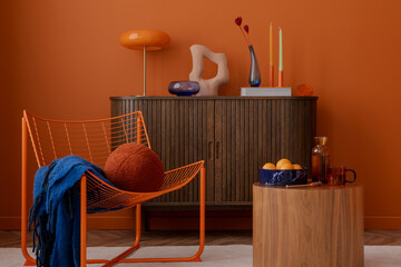 Eclectic and modern living room with a sculptural vibe. Orange wire chair, rounded wooden table,...