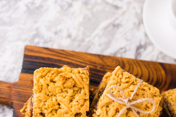 Delicious homemade pie with apple jam. Appetizing slices of grated pie with jam on a wooden board and coffee in a white cup on a light table.