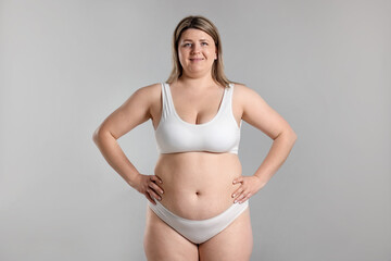 Fototapeta premium Weight loss. Plus size woman in underwear on gray background