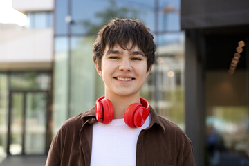 Portrait of happy teenager with headphones outdoors