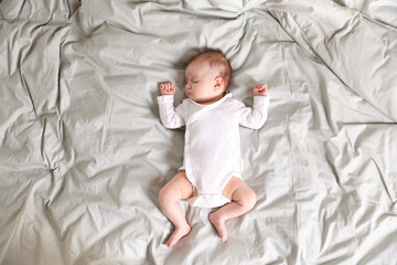 Cute newborn baby sleeping on bed, top view
