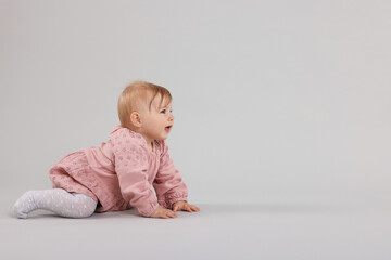 Cute little baby crawling on light grey background, space for text
