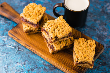 Delicious homemade pie with apple jam. Appetizing slices of grated pie with jam on a wooden board and a cup of milk on the table.