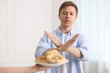 Gluten free diet. Man refusing from pastries indoors, selective focus
