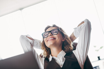 Confident businessman relaxing at a desk in office with glasses and a waistcoat in a bright...