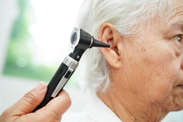 Otolaryngologist or ENT physician doctor examining senior patient ear with otoscope, hearing loss...