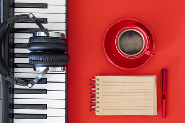 Home studio with headphones and keyboard. Red background minimalist setup.