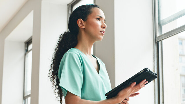 Confident Healthcare Worker Holding Digital Tablet Near a Bright Window in Modern Facility - Powered by Adobe