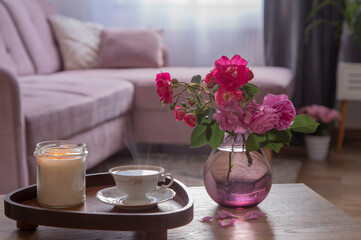 coxy interior with bouquet of roses, burning candle  and cup of coffee
