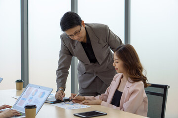 Young secretary and manager in suit meeting around a small table with document paper and tablet computer.