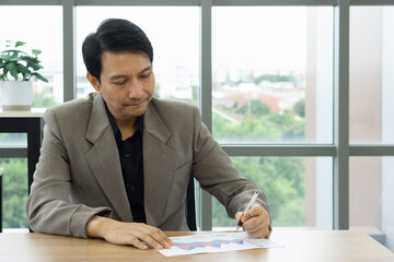 Productive and focused businessman diligently writing on a piece of paper at his desk in a professional setting.