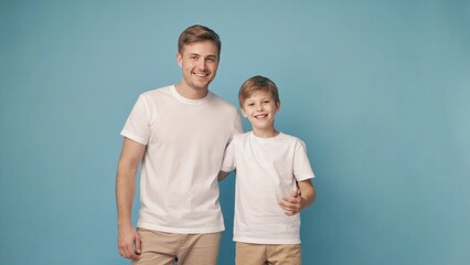 A young Caucasian man and a boy stand together against a blue background. Both wear white t-shirts and light-colored pants, smiling happily.