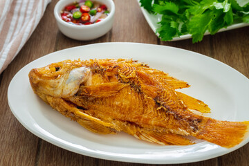 Deep fried red tilapia fish on white plate and dipping sauce