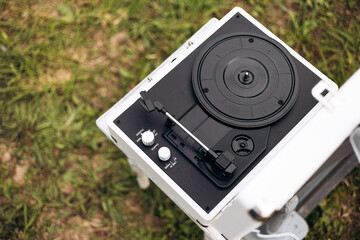 White portable vinyl record player on grass outdoors, retro music picnic.