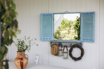 Mirror designed as window with blue shutters hanging on wall, rustic home decor.