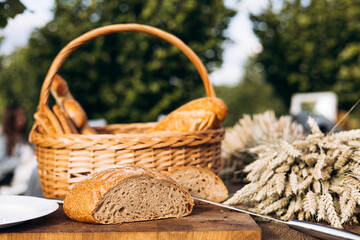 Sourdough bread cut in half and basket with wheat ears, rustic organic bakery.