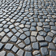 Fototapeta premium Dark stone pavement with glossy cobblestones forming a dynamic curved street pattern