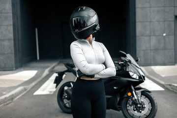 Biker Woman with Helmet posing on street. Cool competitive female motorcyclist wearing protective...