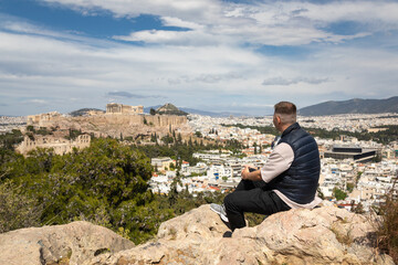 Young man admires the view of the Acropolis from Philopappos Hill