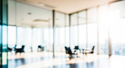Blurred office space with glass walls and large windows showing a city view.